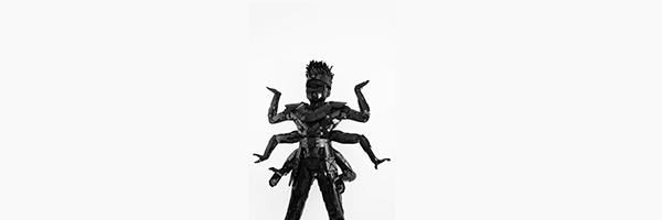 Photo of an installation made of black lego bricks, of a man standing with six arms, representative of Anansi the spider.